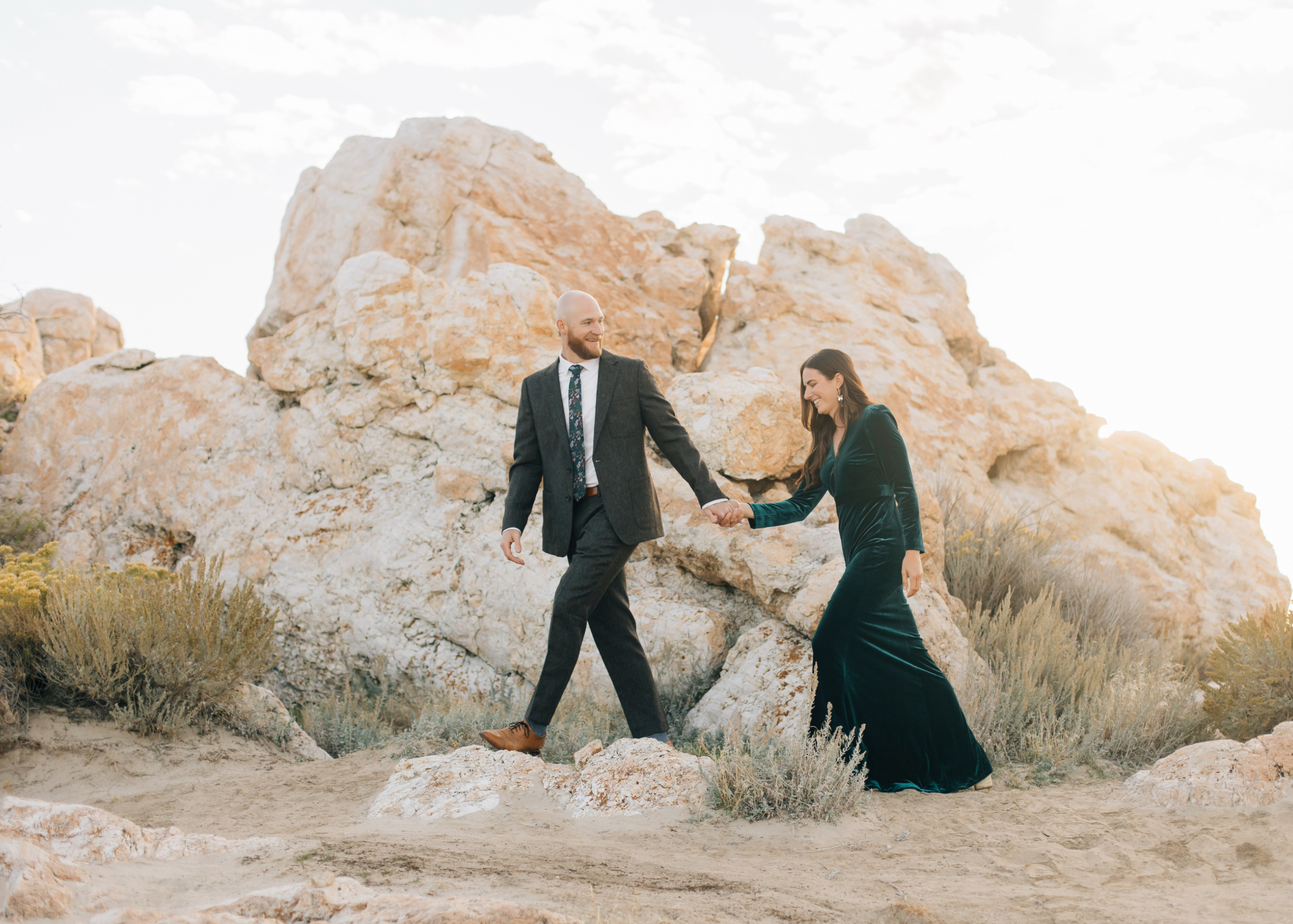 Couple walking along sand with rocks in the background 
formal engagements at Antelope Island